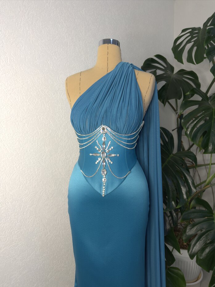 Blue one-shoulder gown with rhinestone chain detail at the waist